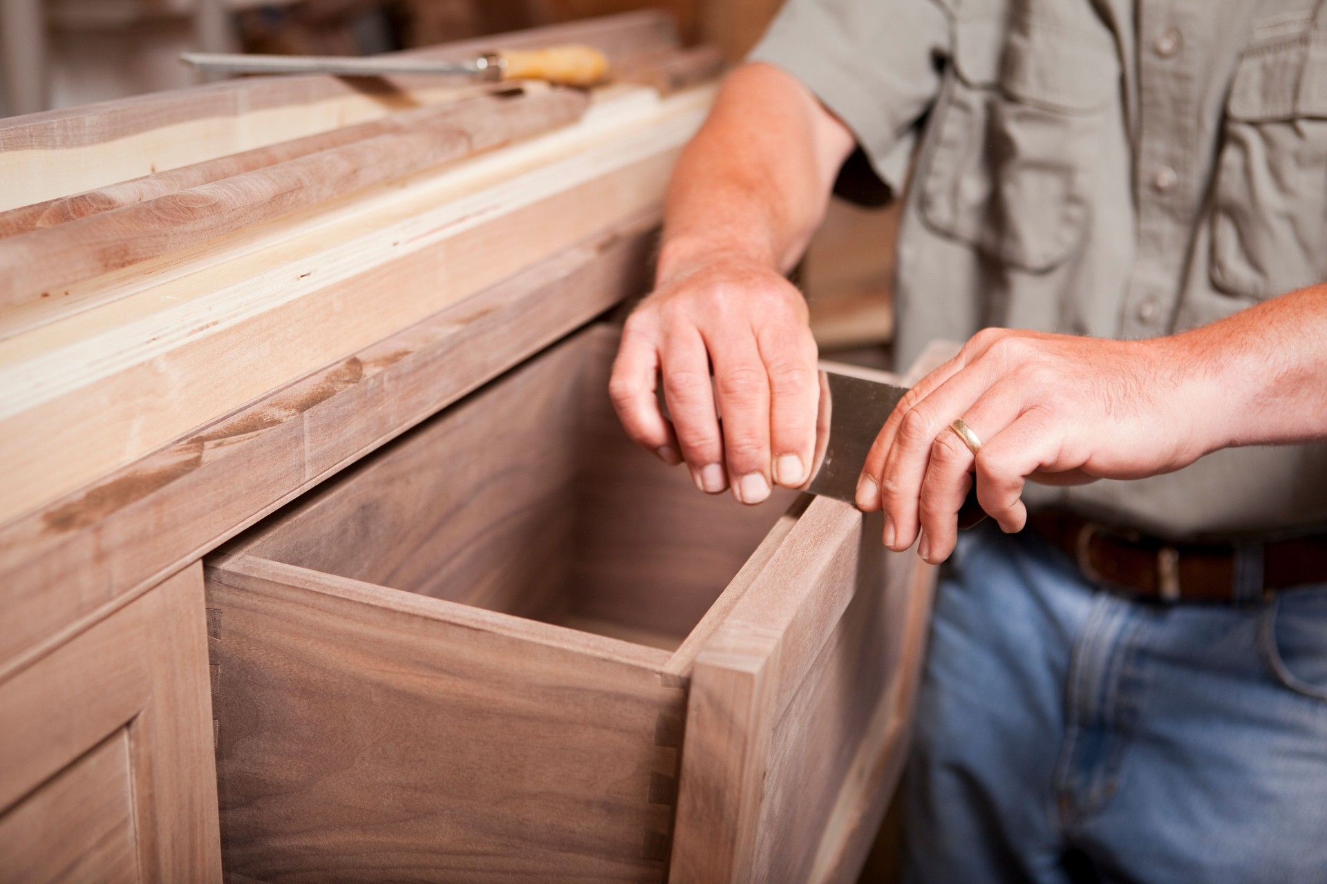 Man smoothing wood cabinet with scraper